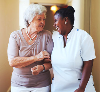 an elderly woman walking with a caregiver woman