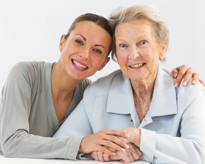 Caregiver smiling together with elderly woman