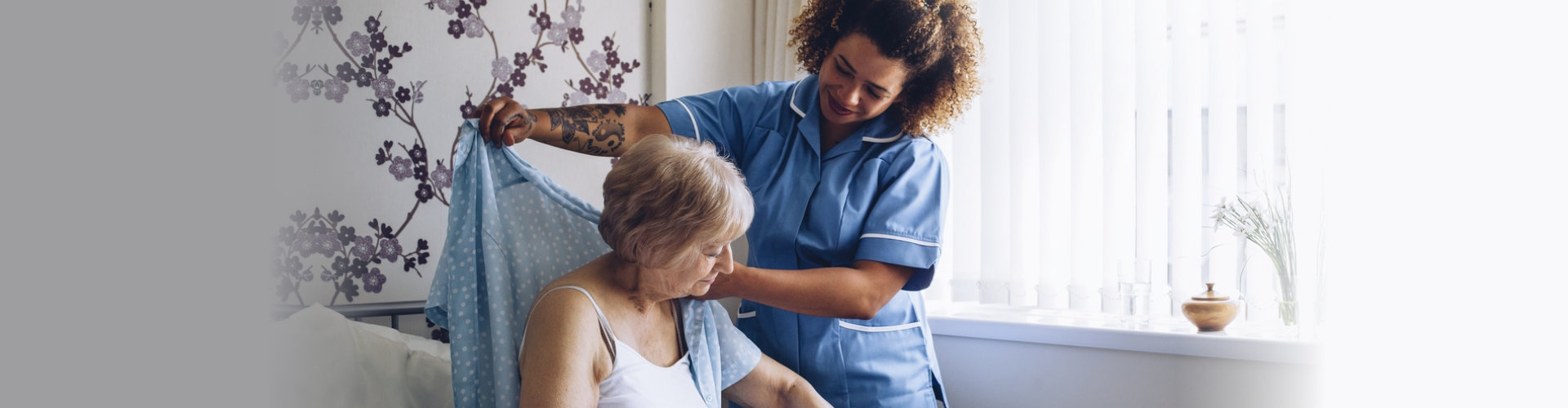 Caregiver helping elderly woman to put on clothes